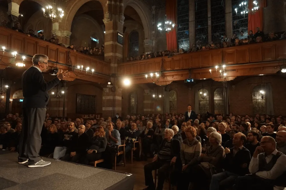 Spreker op podium voor volle zaal in debat- en congrescentrum Arminius Rotterdam