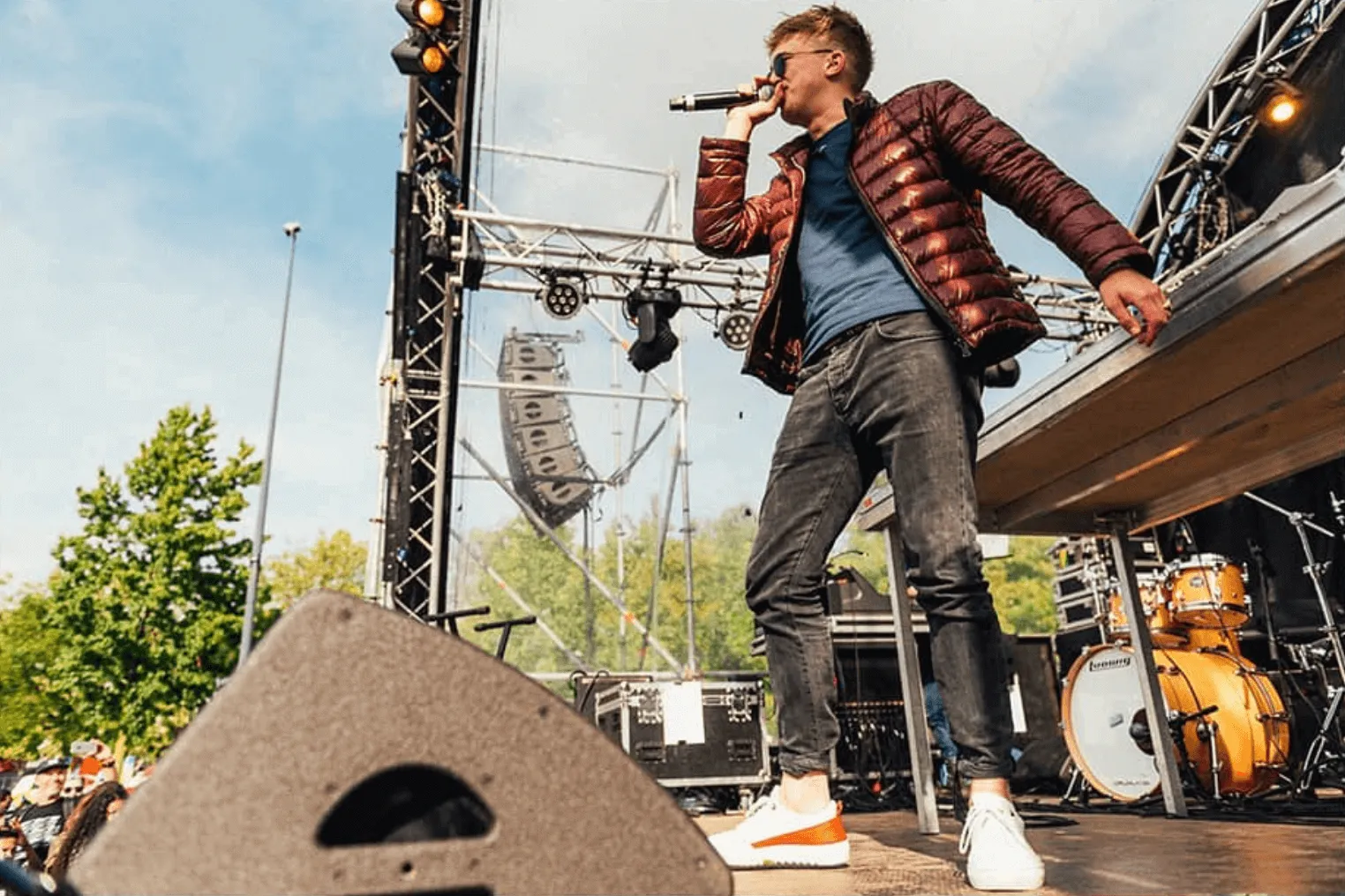 Artiest op een festivalpodium met line-array luidsprekers in de rigging